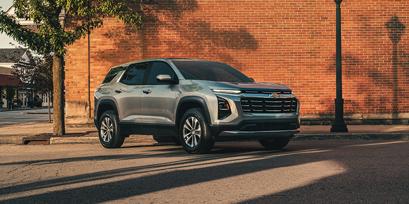 A 2026 Chevrolet Equinox parked in front of a brick building, promoting Spring Vehicle Specials in Fenton, MO.